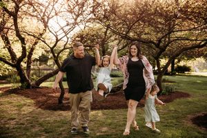 Family walking under a canopy of trees in a Branson, MO park during a spring photoshoot.