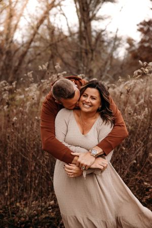 Couple hugging in a rustic autumn field for an engagement photo session in the Ozark Mountains with L. Ballenger Photography.