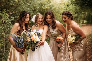 Bride with bridesmaids in gold dresses during an outdoor wedding ceremony in the Branson Ozarks, photographed by L. Ballenger Photography.