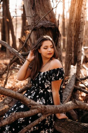 High school senior girl sitting in a rustic wooded setting for a senior photo session in Branson, MO by L. Ballenger Photography.
