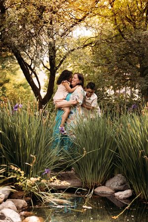 Family hugging in a lush garden setting for a spring photo session in Branson, Missouri with L. Ballenger Photography.