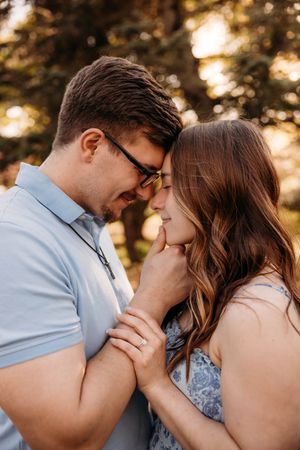 Intimate engagement portrait of a couple in a sun-drenched Branson field, captured by L. Ballenger Photography.