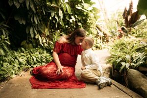 Pregnant Mother and son sitting on a path in a lush garden during a lifestyle photo session in Branson by L. Ballenger Photography.
