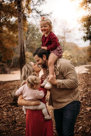 Candid moment of a dad giving his daughter a shoulder ride during a family photo session at a Branson, MO park.
