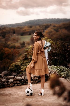 High school senior girl with a soccer ball posing at a scenic Branson overlook during fall.