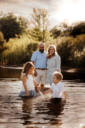 Family playing in a creek at sunset during a lifestyle photo session in the Branson Ozarks, captured by L. Ballenger Photography.