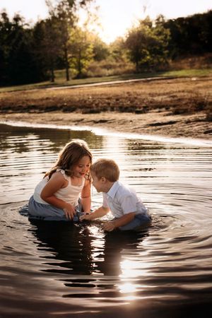 Two young children playing in the shallow water of Table Rock Lake during a sunset family photo session in Branson, MO.