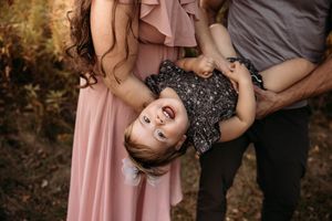 Laughing child held upside down during a playful family photo session in Branson, MO by L. Ballenger Photography.