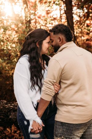 Close-up of an engaged couple kissing in the autumn woods of Branson, MO at sunset.