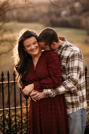 Romantic engagement photo session at a rustic Branson, MO fence line during golden hour.