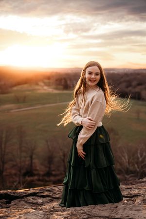 Young girl posing on a rocky overlook at sunset for a scenic Ozark Mountain photo session in Branson.