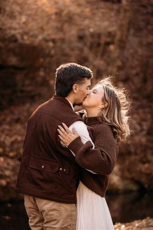 Engaged couple kissing in the woods for a cozy fall photo session in Branson, MO.