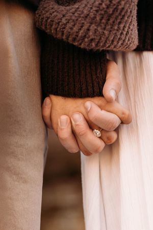 Close-up of an engaged couple holding hands during a cozy fall photo session in Branson, Missouri by L. Ballenger Photography.