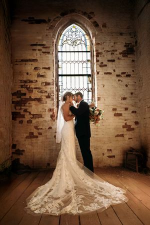 Bride and groom embracing under a historic stone arch at a Branson MO wedding venue.