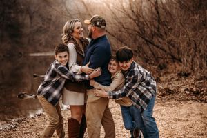Candid family moment of parents hugging their sons in the autumn woods of the Ozark Mountains.