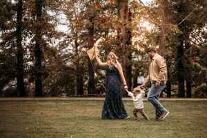 Family of three walking across a scenic Branson lawn during an outdoor golden hour photoshoot.
