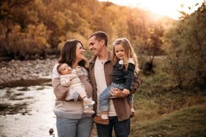 Branson family photographer capturing a family of four by a scenic creek at golden hour