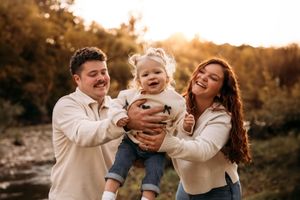 Warm, backlit family portrait in a Branson field featuring ivory and tan fall outfits.