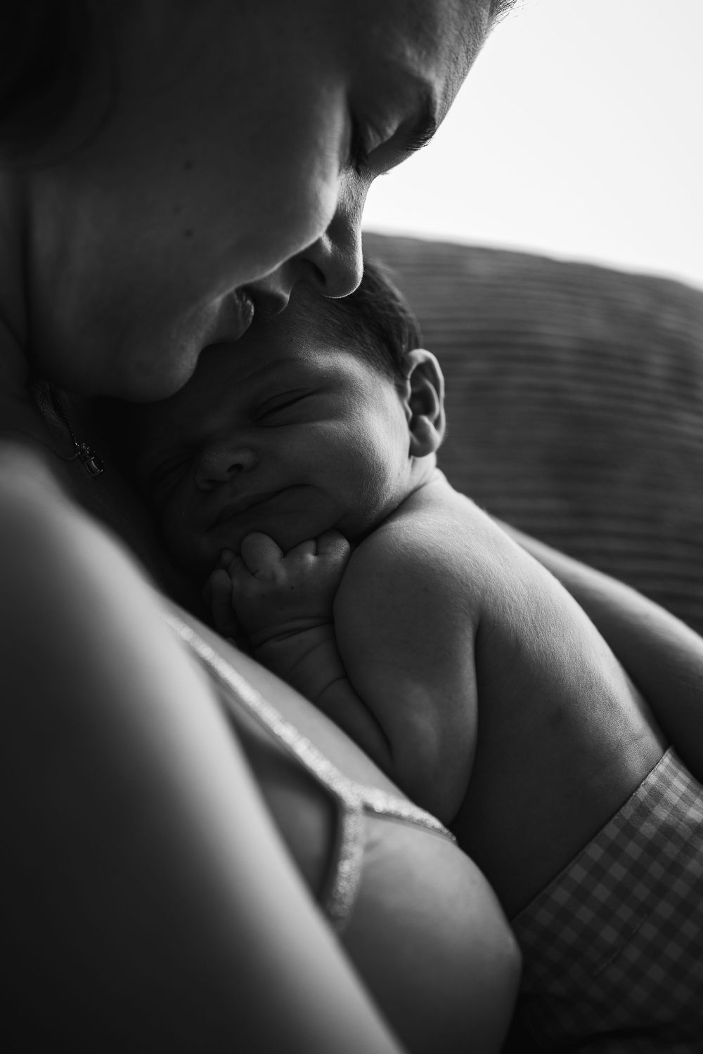 Intimate black and white photos showing tender moments between parent and infant in soft lighting.
