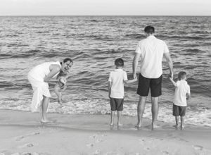 Black and white photo of a family of 5 playing on the beach in Perdido Key. Florida