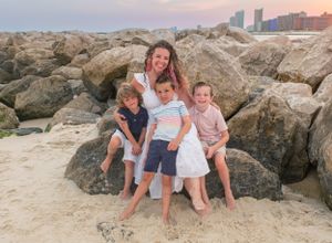 A woman sits on boulders with boy and girl children at the jetty at Alabama Point or Perdido Pass in Orange Beach, Alabama