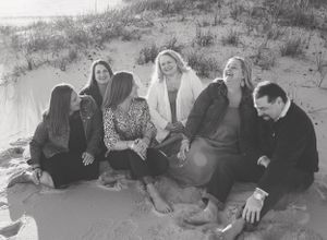 A black and white photo of a group of friends having a laugh on the sand dune in Orange Beach Alabama