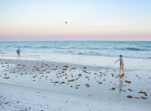 Two boys play catch on the wet sand beach of Pensacola Beach, pensacola beach family photographer, pensacola beach candid family photography