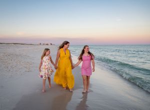 A mother and daughters walk down the beach at sunset in Orange Beach, Alabama