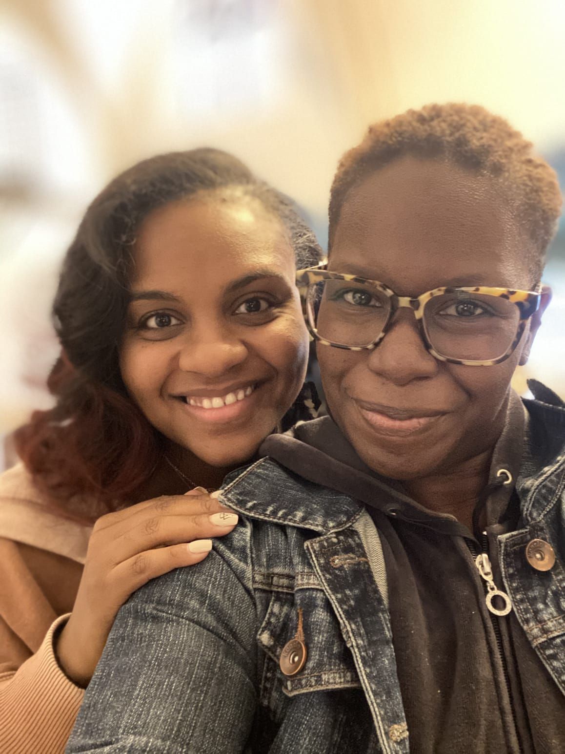 Close-up selfie of two people smiling warmly in casual attire.