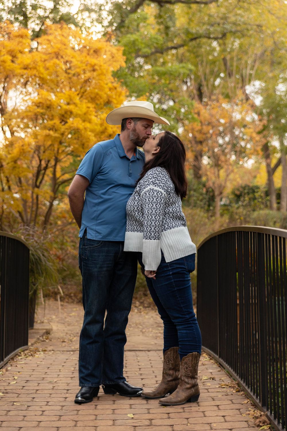 A couple kisses on a bridge.