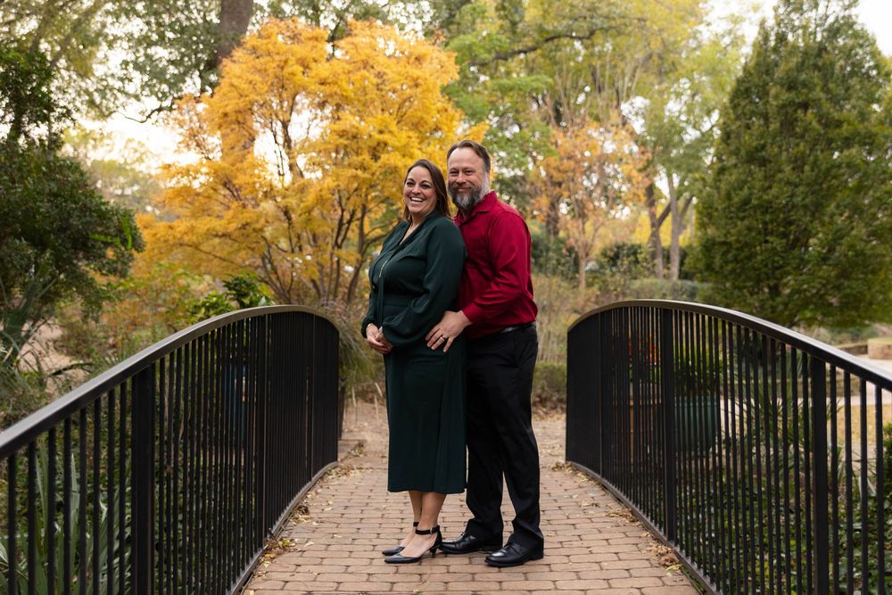 A couple poses on a bridge.