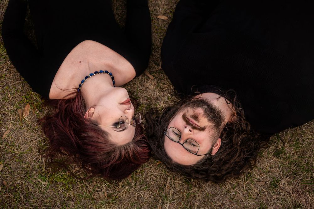 A couple poses laying in the grass.