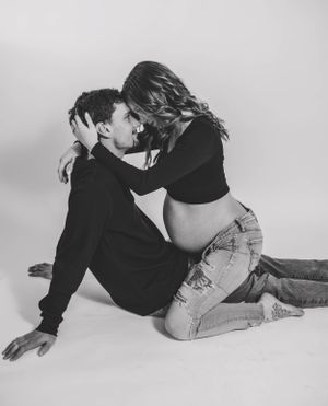 Intimate black and white maternity photo with couple embracing on studio floor.