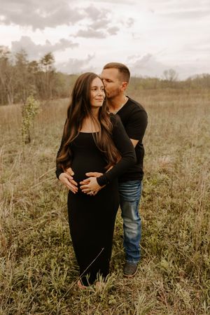 Intimate couple embracing in a field during golden hour.