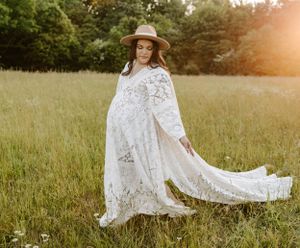 Ethereal maternity photo of woman in flowing lace dress and hat in sunset meadow.