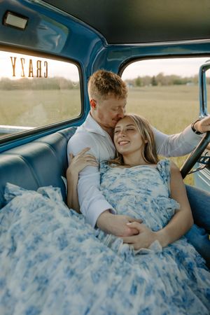 Couple sharing intimate moment inside vintage blue truck interior.