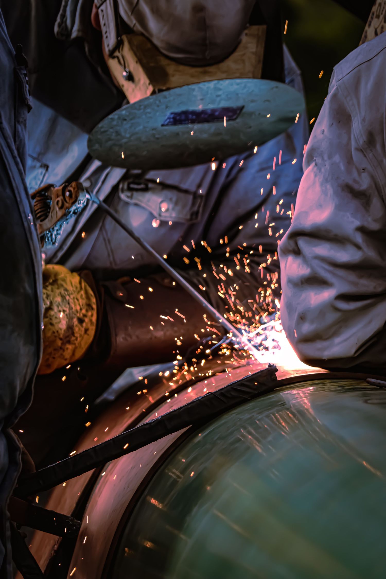 Metal fabrication sparks fly during welding work with protective gear.