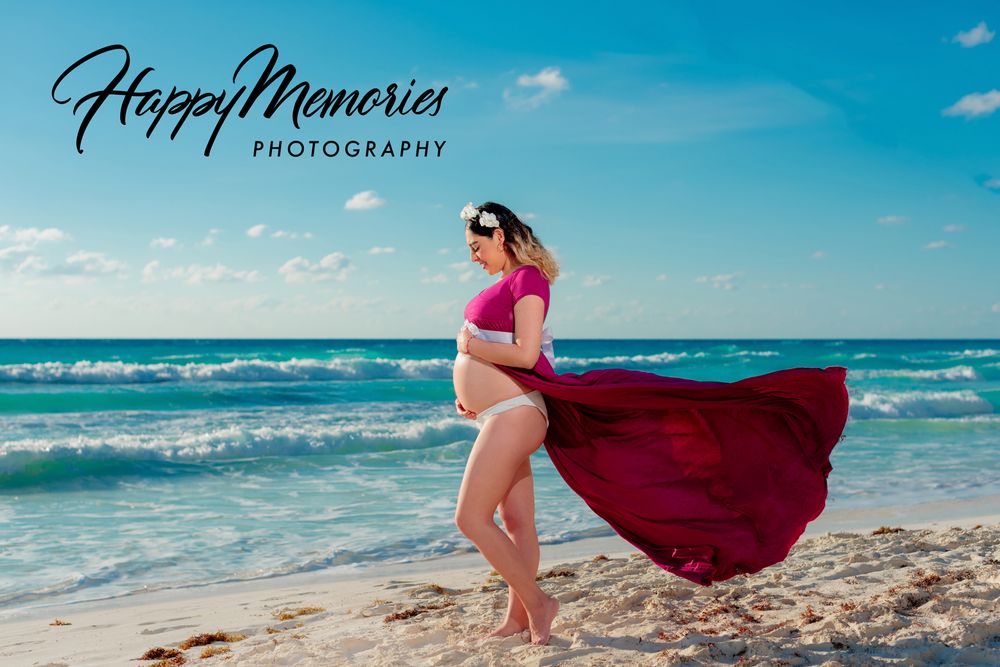 Dramatic red fabric flowing in beach maternity photoshoot.