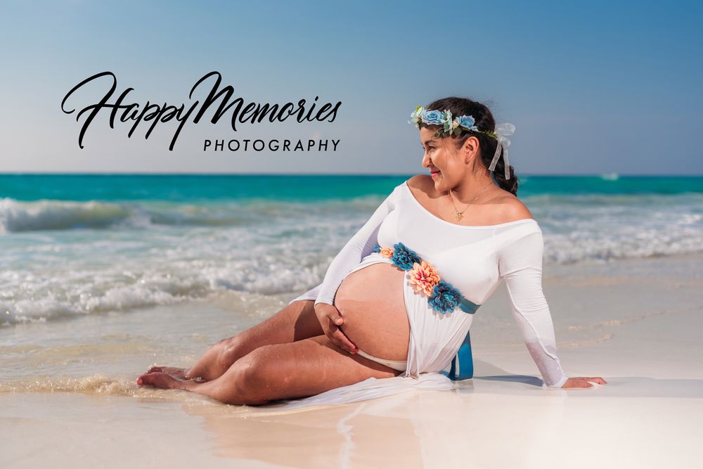 Artistic beach maternity photos with white flowing fabric against ocean waves.