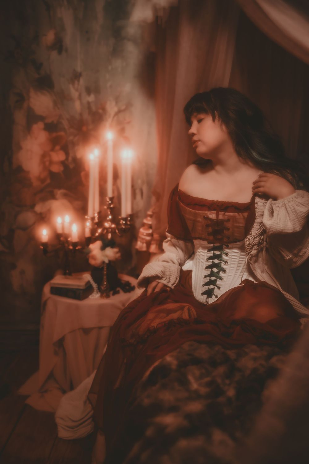 Woman in Renaissance corset gown by candlelight, evoking a dramatic, historical atmosphere.
