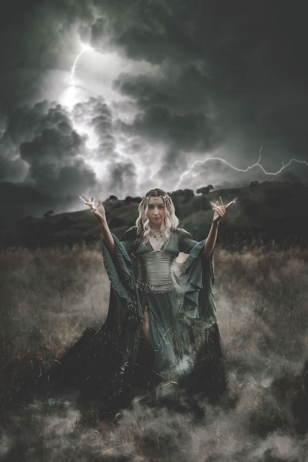 A mystical woman in a flowing teal gown raises her hands dramatically in a stormy field with lightning behind her.