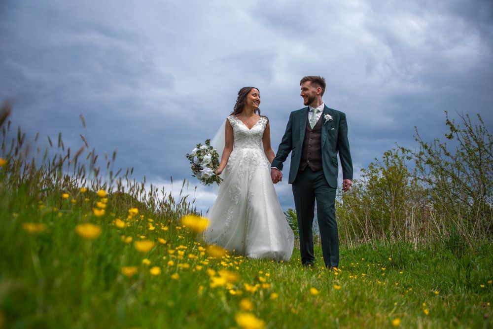 Bride and groom walking through flowers at Brickhouse Vineyard, Devon