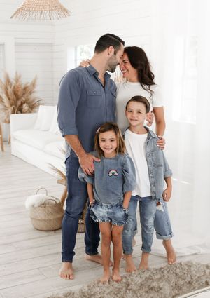 Casual family portrait in coordinated denim and white outfits against bright modern coastal decor.