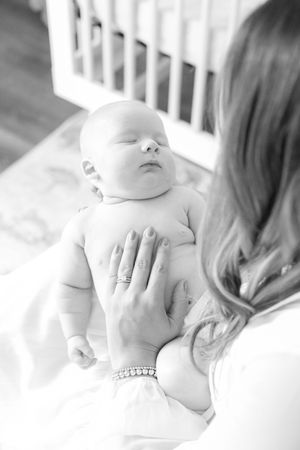 Black and white image of sleeping infant being gently touched by caregiver.