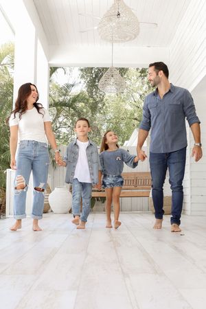 Candid family walking shot on white porch wearing coordinated casual outfits in blue and white.