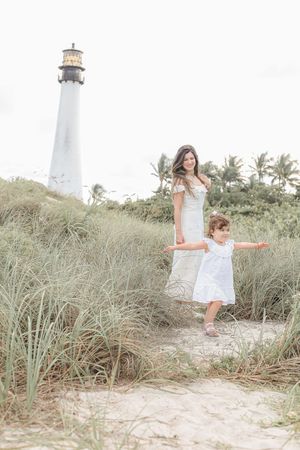 Coastal portrait with tall lighthouse and palm trees featuring coordinated white summer outfits.