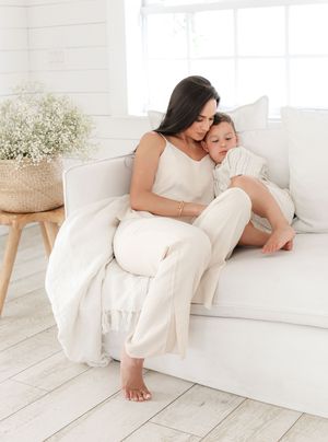 Mother and child sharing tender moment while relaxing on white couch.