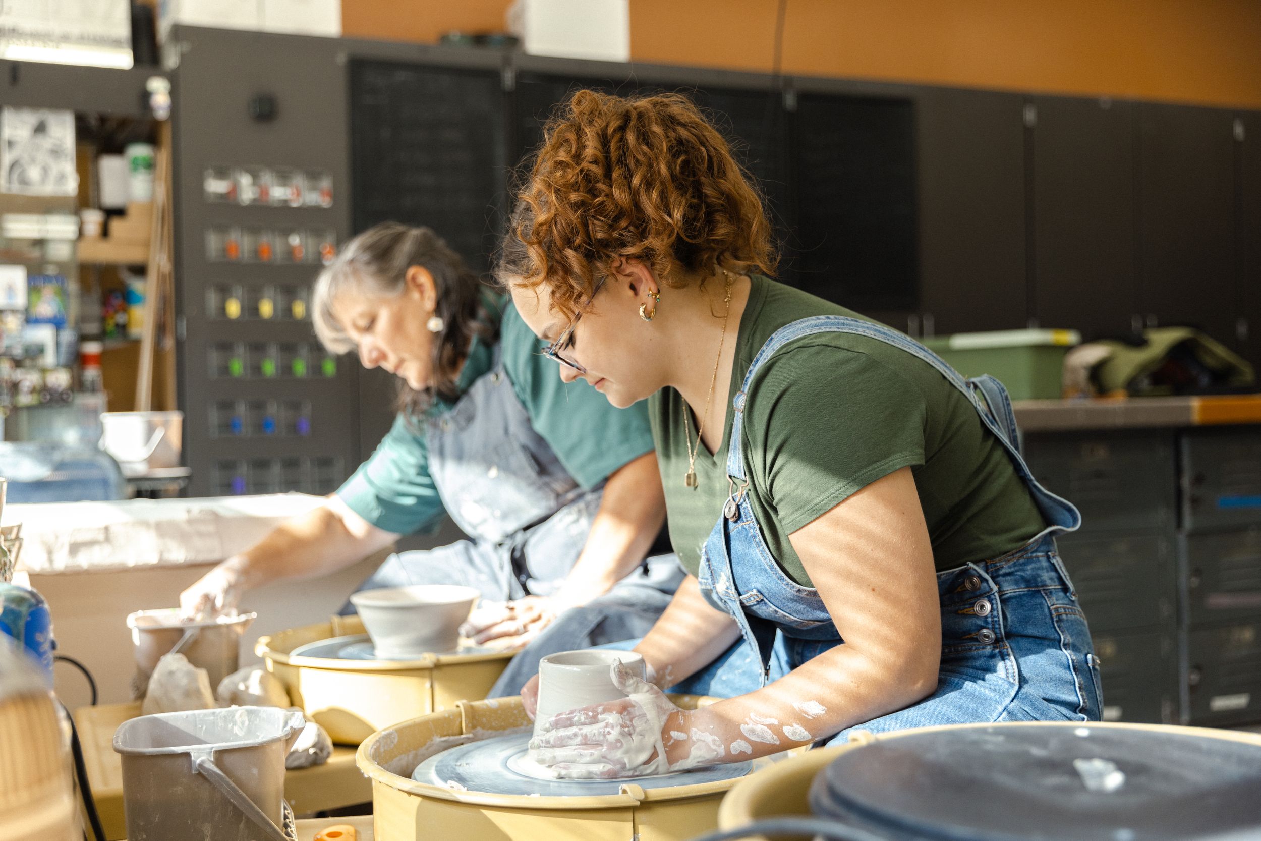 Student with teacher in the pottery studio at the Valley Highschool in West Des Moines, Iowa for unique senior photos