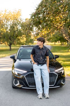A sleek dark gray Audi car parked outside waterworks park in Des Moines, Iowa for Drew's senior photos