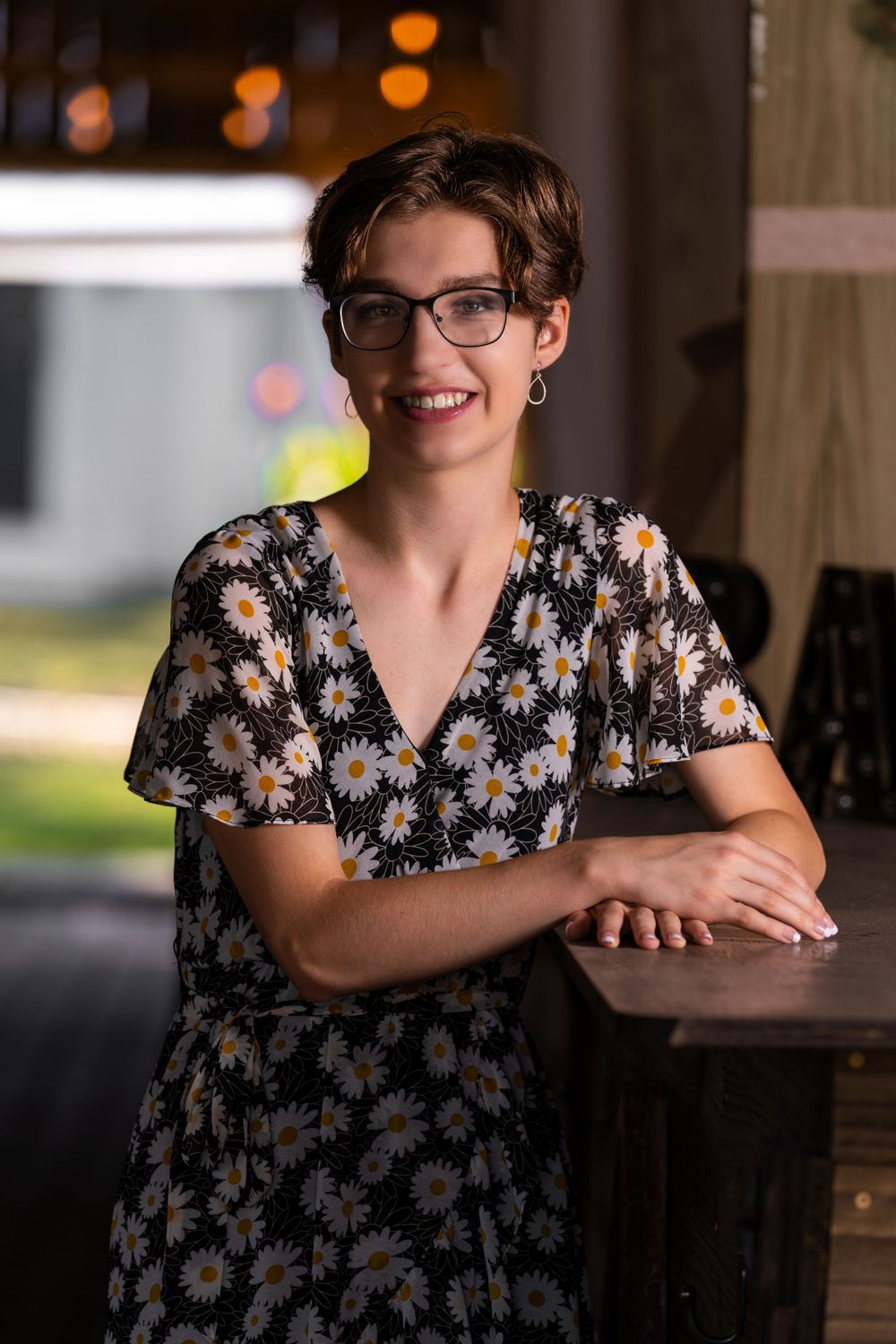 A charming portrait with a floral dress in a warm evening setting with bokeh lights.